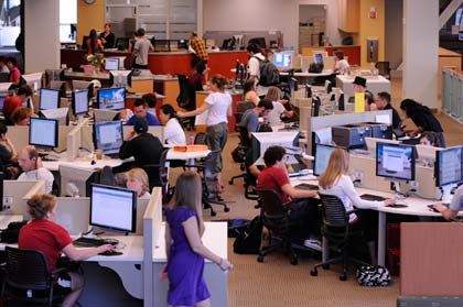 People studying at computer desks in a busy library setting.