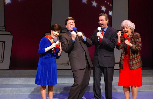 Four people holding microphones on a stage. image link to story