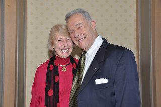 A smiling couple, one wearing a red outfit and scarf.