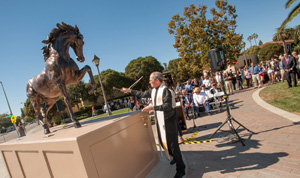People gather around a statue of a rearing horse outdoors. image link to story
