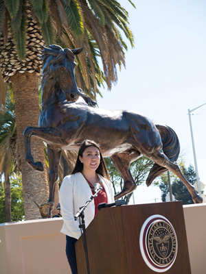 Person standing by a bronco statue with a podium displaying a seal.