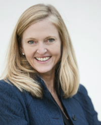 A smiling person in a blue suit jacket.