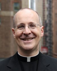 A smiling person wearing a clerical collar and glasses. image link to story