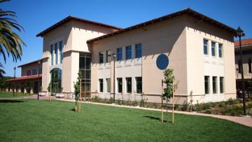 A modern two-story building with large windows under a clear blue sky.