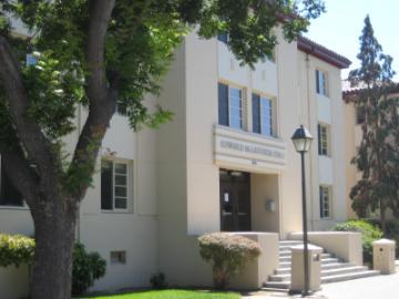 A beige building with trees in the foreground.