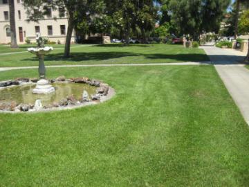 A well-manicured garden with a path and a historical building in the background.