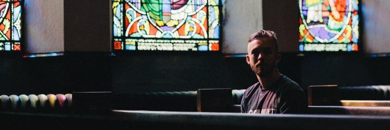 Man sitting at a desk in a room with large windows.