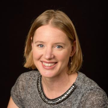 A smiling person in a professional headshot against a black background.