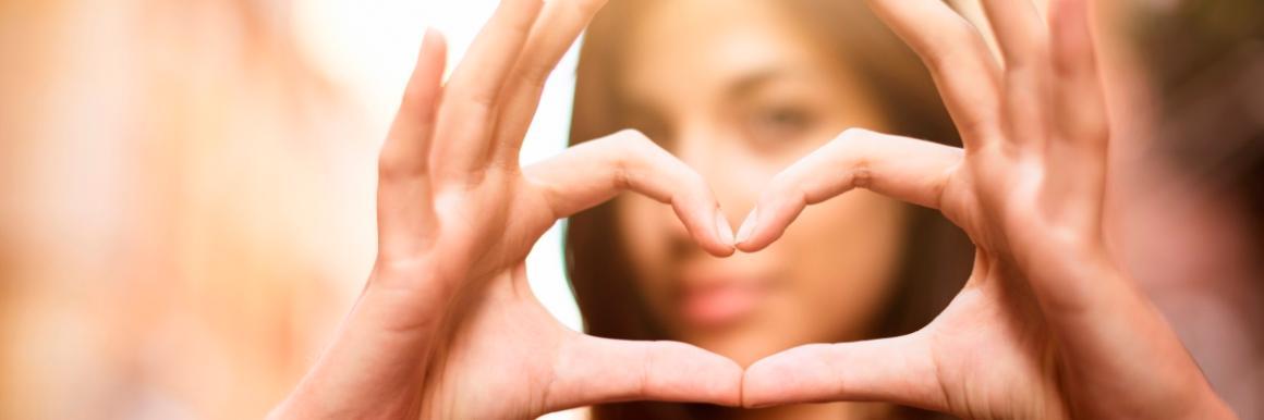 Woman making heart shape with hands in front of her face.