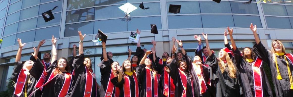 A group of graduates in caps and gowns celebrate by tossing hats.