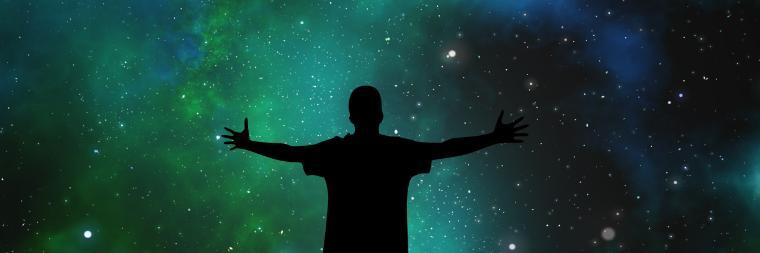 Silhouette of a person with arms outstretched against a starry night sky.