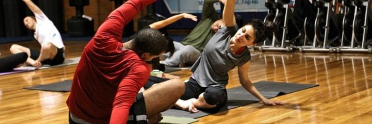 People in gym stretching on yoga mats.