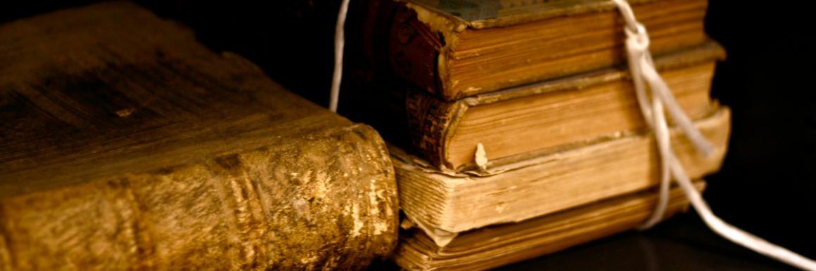 Close-up of stacked old books with a frayed rope beside them.