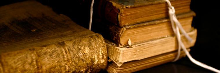 Close-up of stacked old books with a frayed rope beside them.