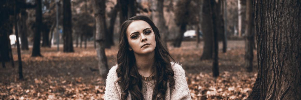 Woman sitting in the forest looking annoyed