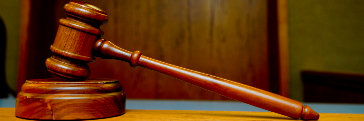 A gavel resting on a wooden block in a courtroom.