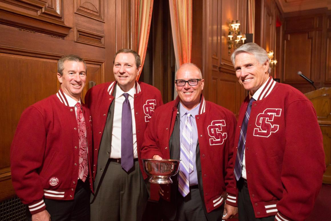 Four men in red jackets posing for a photo at an award event.