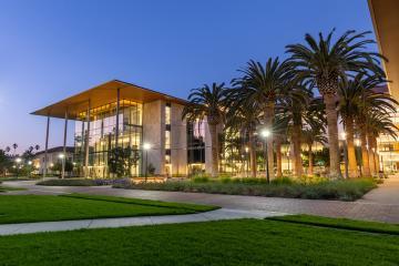 The image shows the Sobrato Campus for Discovery and Innovation (SCDI) building at night.