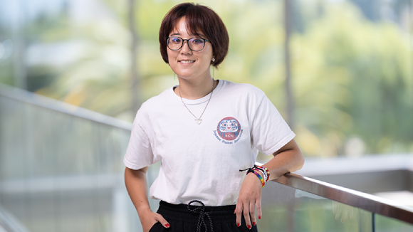 A young person of Asian descent in a t-shirt by a balcony