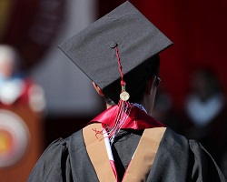 Back of a person wearing a tradition graduation cap and gown.