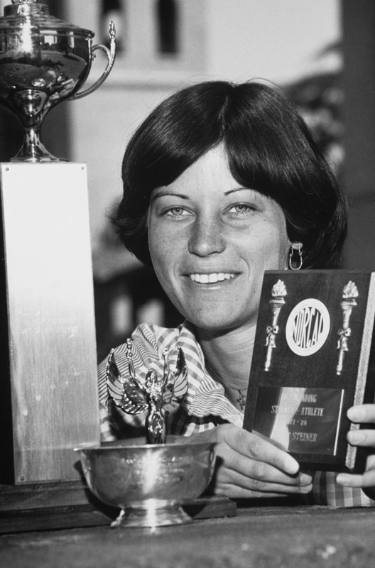 Smiling person holding a small trophy and a can with Swiss emblem.