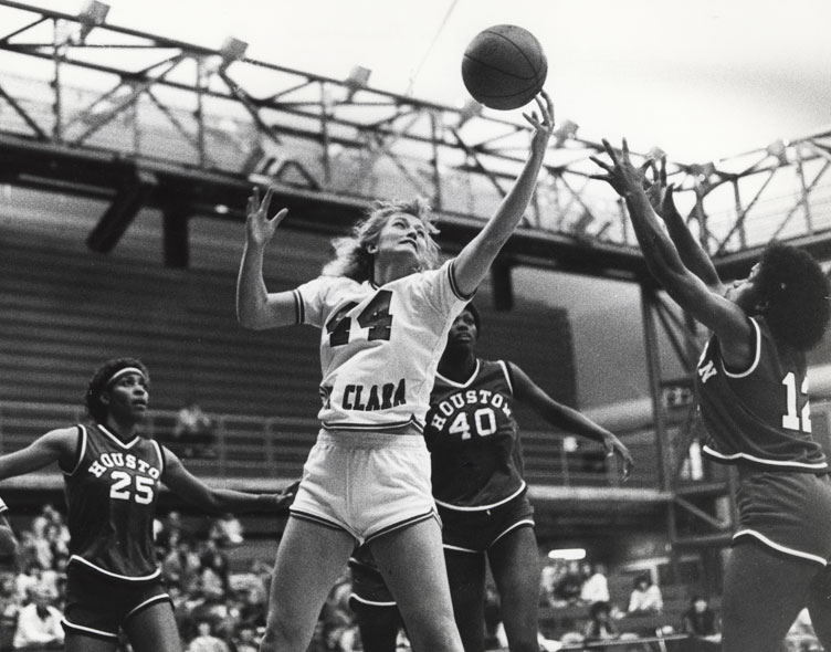 Black and white photo of a basketball game, player jumping to catch the ball.