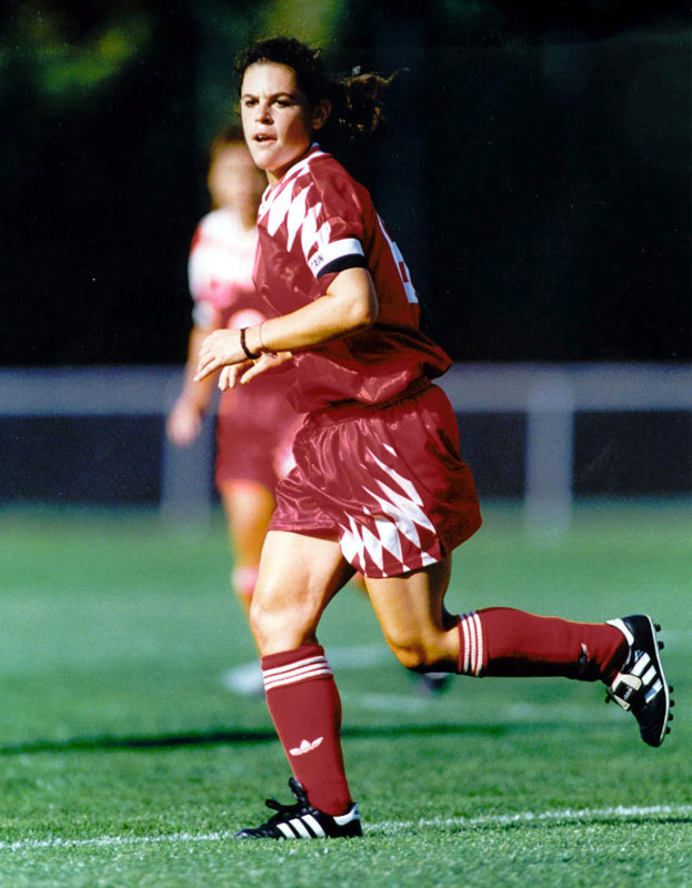 Soccer player in red uniform running on the field during a match.