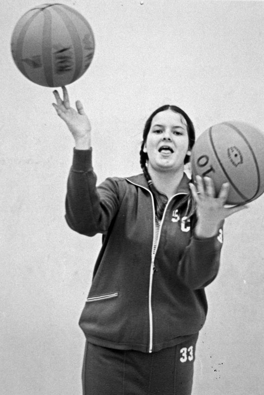 Person balancing a basketball on one finger while holding another basketball.