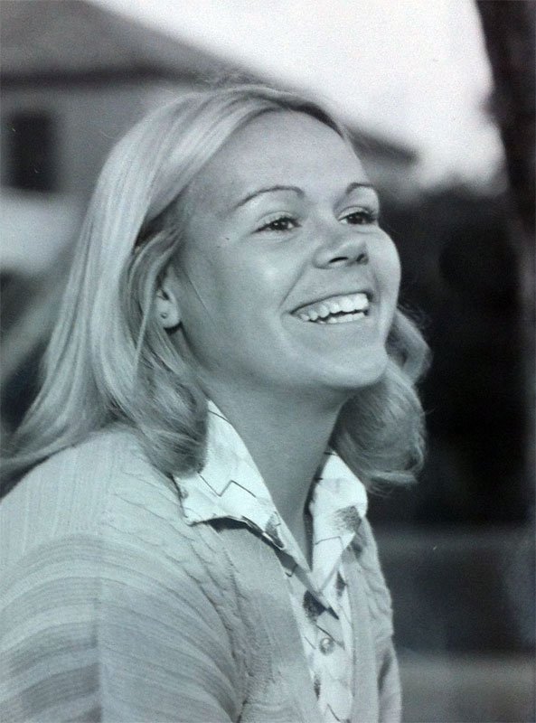 Black and white photo of a smiling person outdoors.