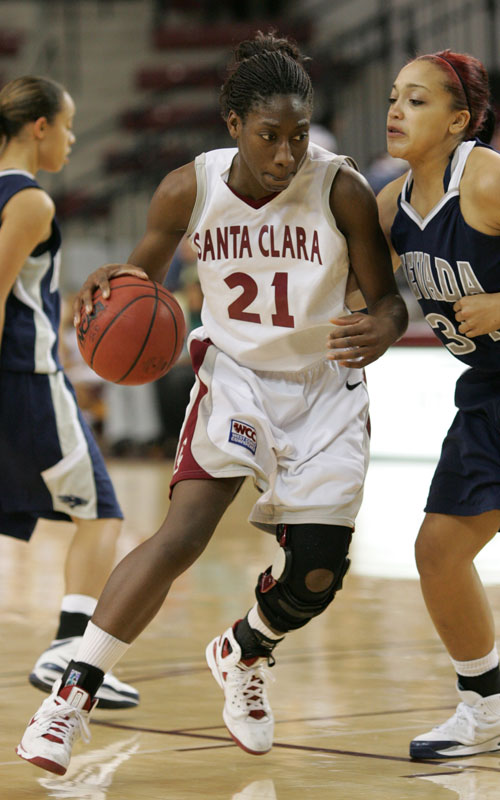 Basketball player in white jersey dribbling past two defenders.