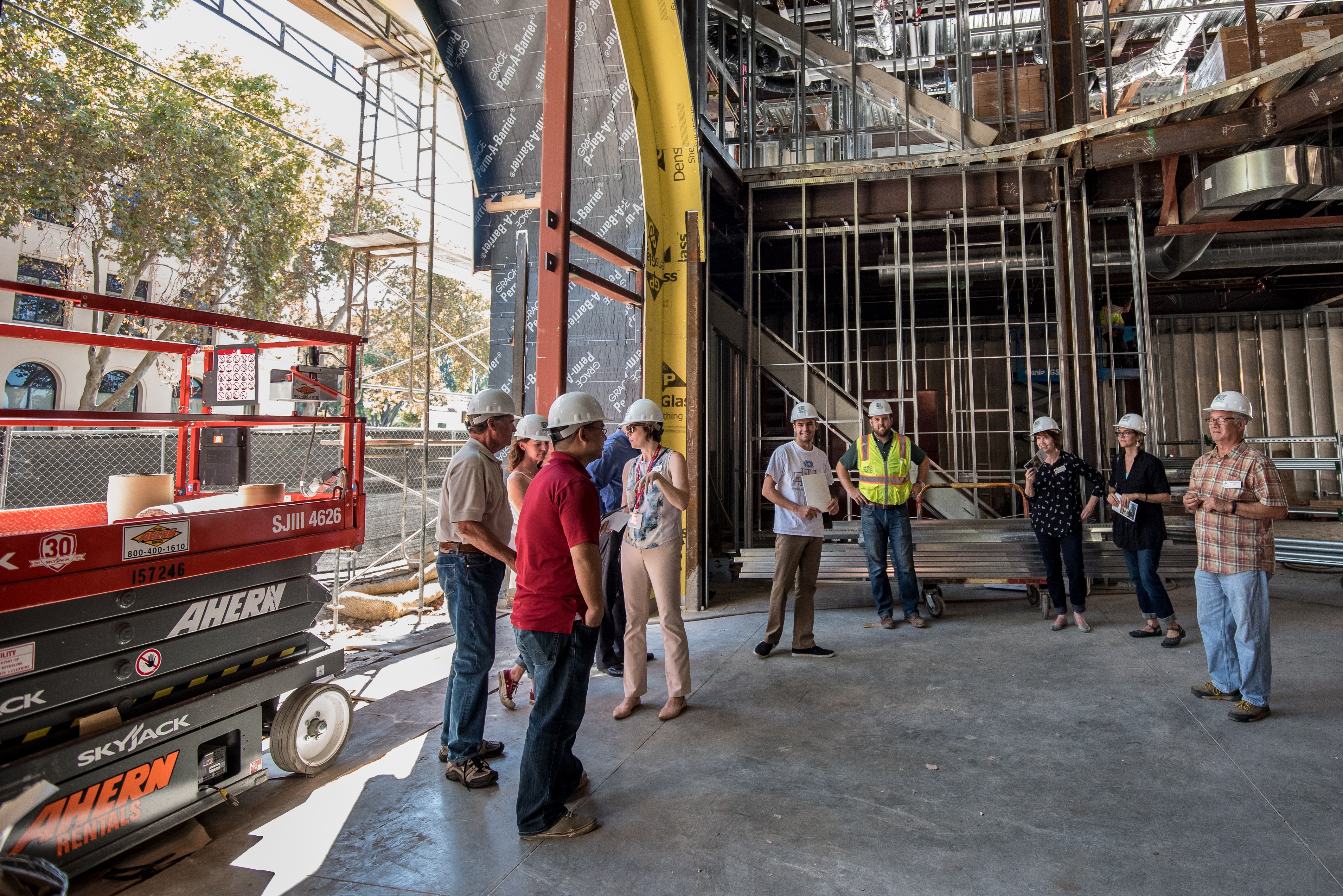 People looking at a red streetcar inside a picturesque urban building.