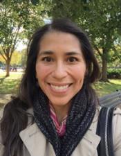 Smiling person outdoors with trees in the background.