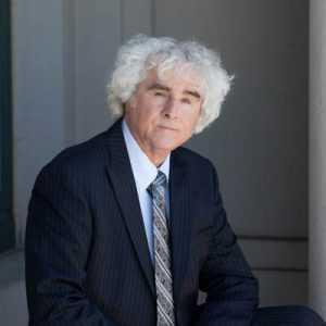 An older white haired man in a suit and tie.