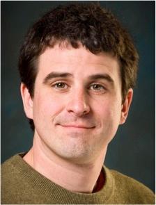 A person wearing a green shirt against a dark background.