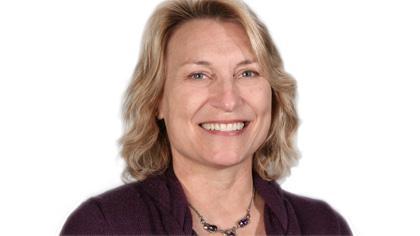 A woman smiling, wearing a necklace and dark blazer against a white background.