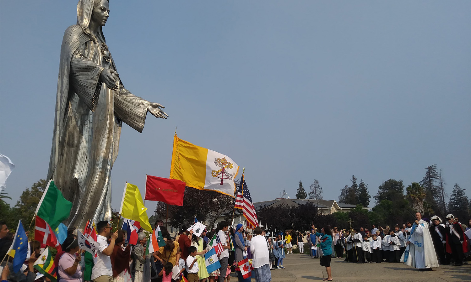 A community gathering near a large statue with colorful decorations.