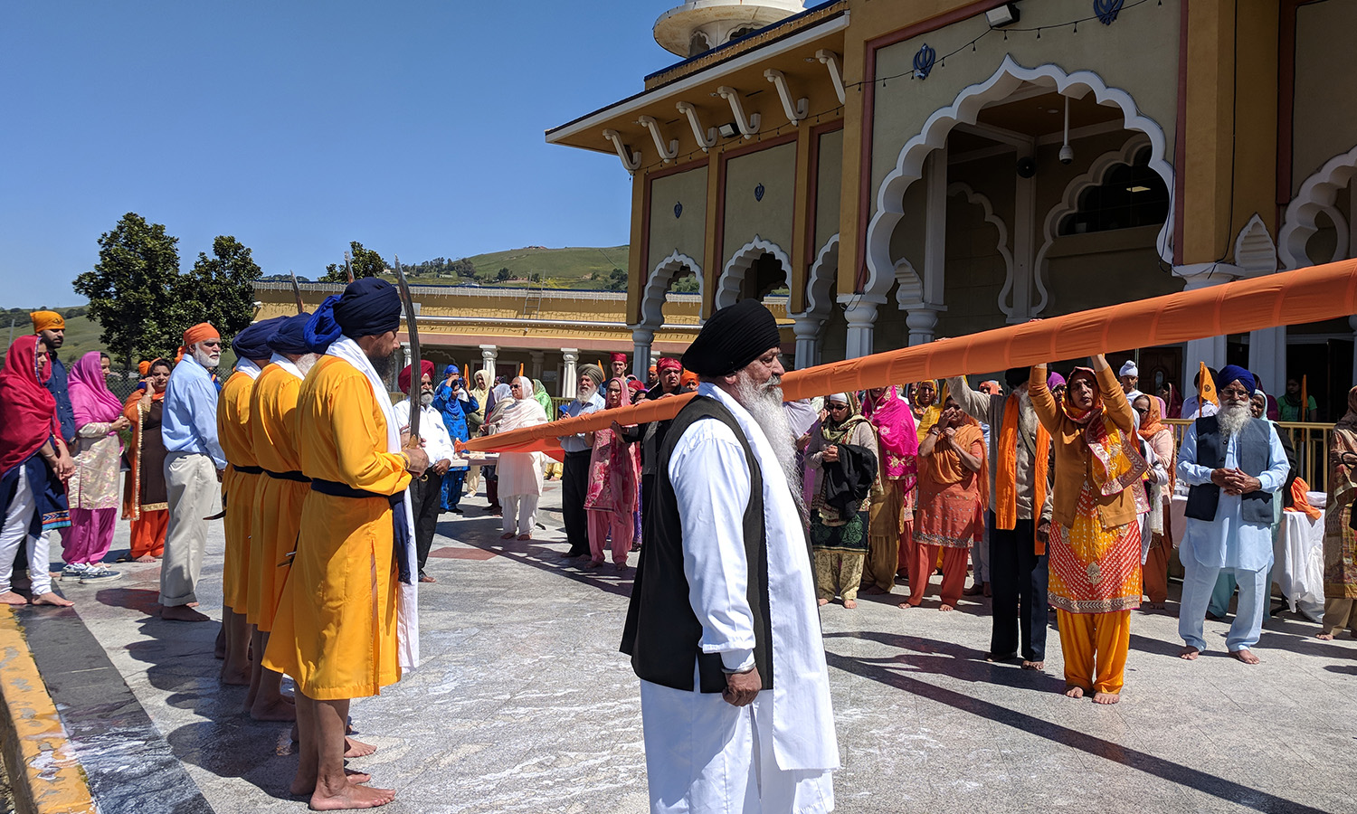 People gathered outside a Sikh gurdwara with colorful attire.