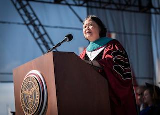 A person speaking at a podium during a graduation ceremony.