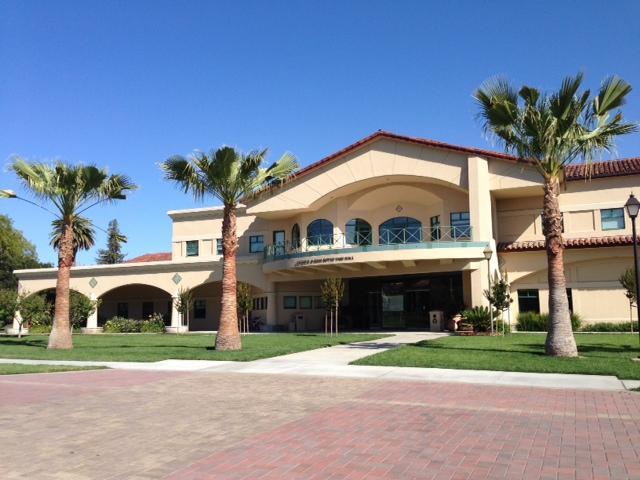 A large beige building with palm trees in front.