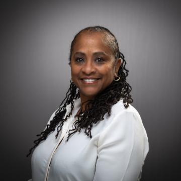 A person smiling in a white shirt against a gray background.