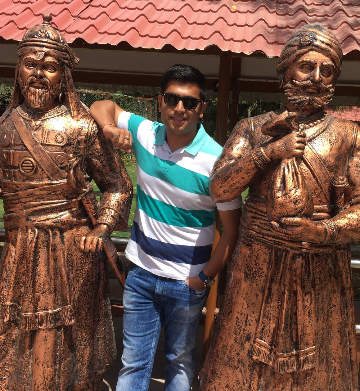 Person posing between two bronze statues.