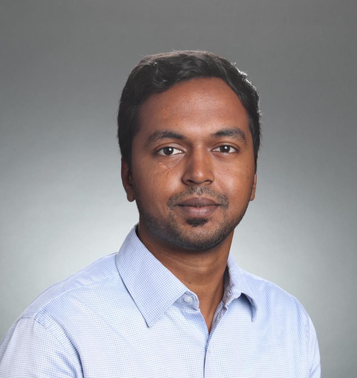 A person wearing a white shirt against a plain background.