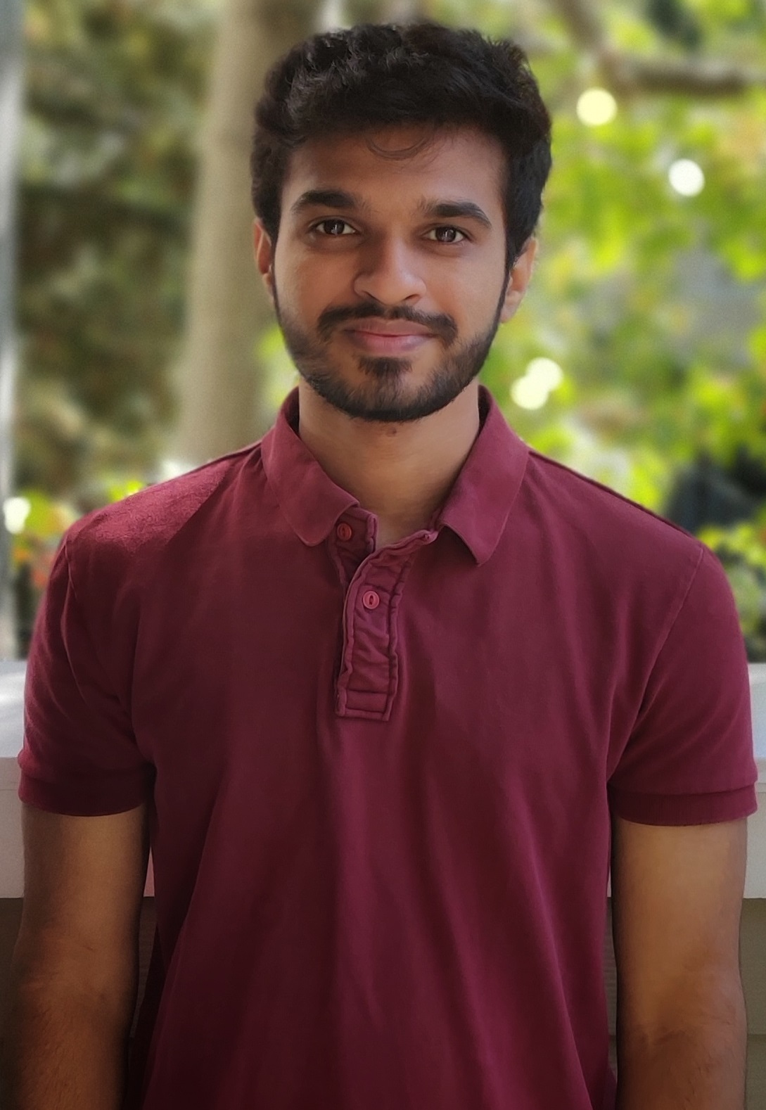 A person in a maroon shirt standing outdoors.