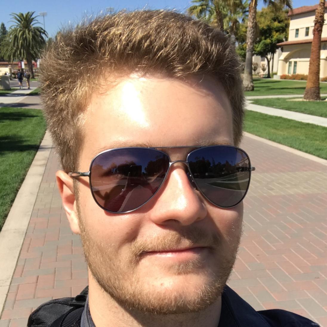 A person wearing sunglasses outdoors on a sunny day.