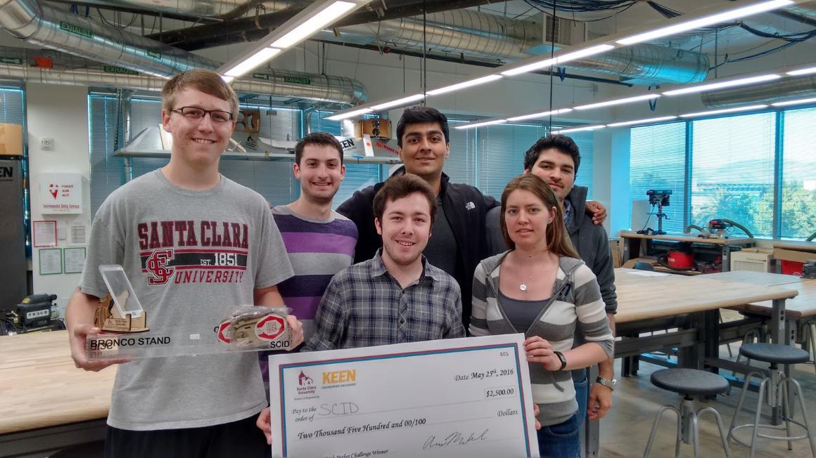 A group of six people celebrating with a large check.