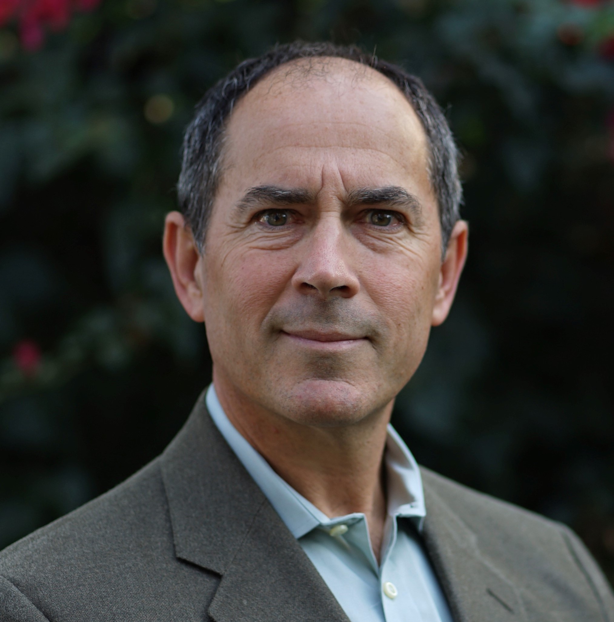 A person wearing a suit, posing outdoors.