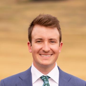 A person in a suit smiling at the camera.