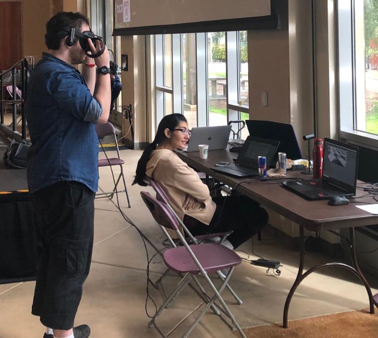 Two people working with cameras and computers next to windows.