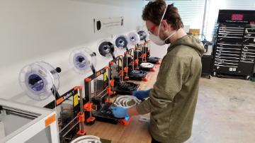 Student removes face shield parts from 3D printer