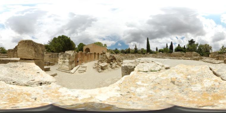 Panoramic view of ancient ruins in Gortyn, Crete, with stone structures and cloudy sky.